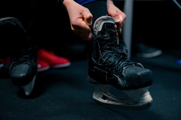 Close-up of a player getting ready by tying ice skates in a hockey dressing room.