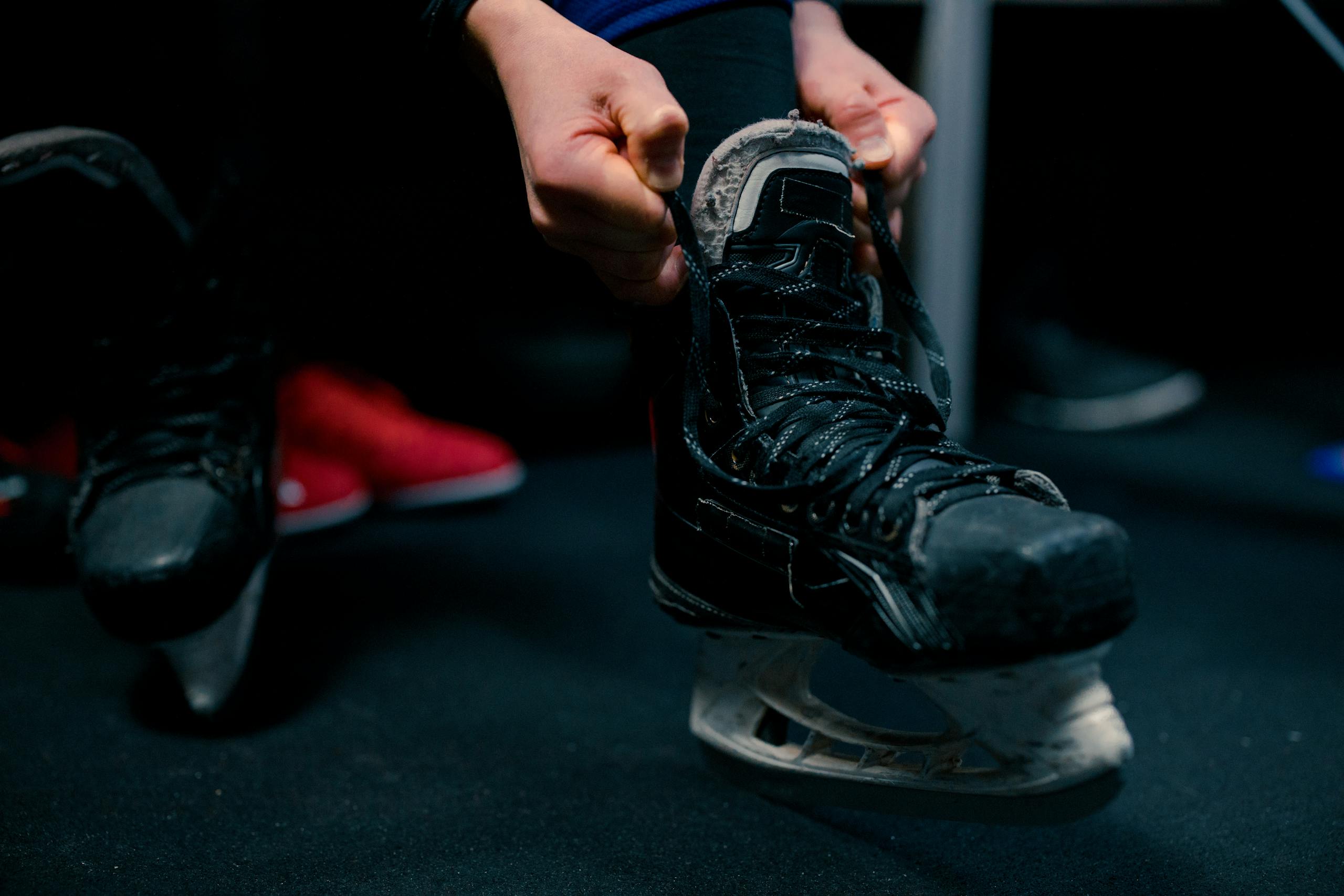 Close-up of a player getting ready by tying ice skates in a hockey dressing room.